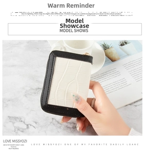 Close-up of white crocodile pattern card holder with gold zipper on marble surface