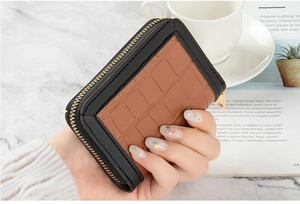 Detailed close-up of small crocodile pattern wallet with gold zipper and leather trim