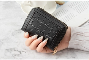 Close-up of black faux crocodile leather card holder with gold U-shaped zipper detail