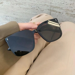 Close-up of black oversized square sunglasses with signature silver rivet details