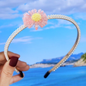 Macro detail of hand-woven pearl headband with pink-yellow beaded floral embellishments