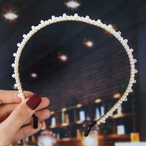 Detail of a gold headband featuring delicate rows of white faux pearls and secure black tips