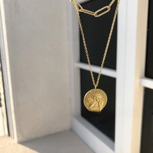 Macro detail of gold-plated cupid angel relief coin pendant on titanium steel chain