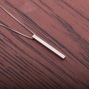 Detailed view of mirror polished silver rectangular pendant on a wooden background