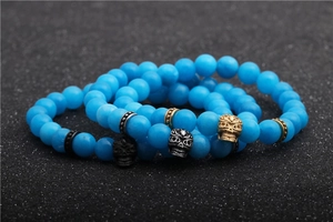 Detail of 8mm blue matte agate beads featuring gold and silver skull charms