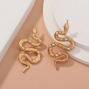 Detailed macro shot of vintage matte gold snake earrings with white pearl accents
