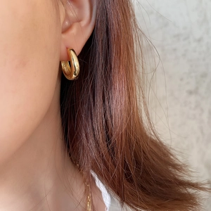 Close-up of minimalist gold-plated 925 silver wide hoop earring worn by a model