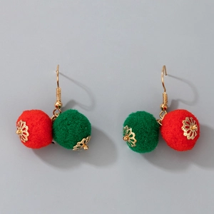 Detail view of festive earrings featuring soft red and green pom poms with golden metal hooks
