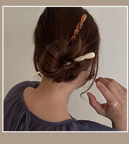 Detail of twisted acetate hair sticks in amber and cream white for elegant styling
