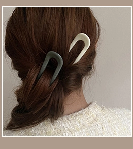 Back view of a woman wearing U-shaped acetate hair pins in a low bun hairstyle