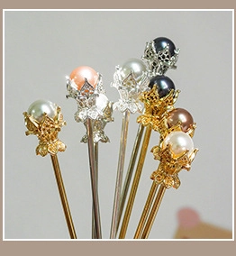 Detailed macro shot of vintage pearl hair pins with gold and silver crown floral metal bases