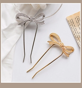 Detail of silver rhinestone and golden beaded bow-shaped hair pins on white silk