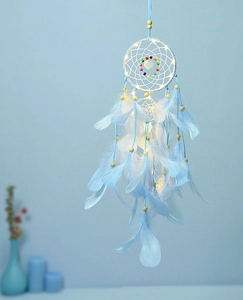 Blauer Traumfänger mit LED-Lichtern und weichen Federn an einer pastellfarbenen Wand