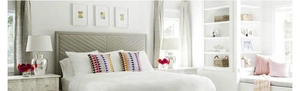 Detailed view of grey fabric headboard and modern white bedding with geometric pillows