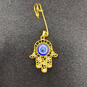 Detailed view of Hamsa Hand brooch with blue evil eye and clear zircon stones in gold