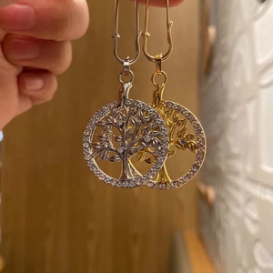 Detailed close-up of Tree of Life pendant with white crystals in gold and silver finish