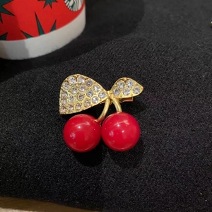 Cute red cherry brooch with gold bow and sparkling rhinestones on black fabric