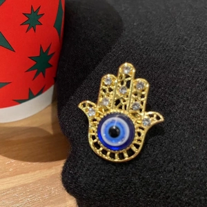 Golden Evil Eye brooch with blue eye and crystals pinned on black knit fabric