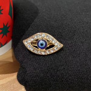 Macro detail of blue evil eye brooch with crystal rhinestones on gold alloy base