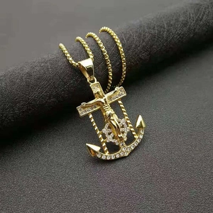 Gold plated hip hop anchor cross pendant with crystals on a black textured background