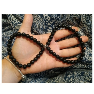 Detailed view of an 8mm black stone bead bracelet with silver accent on fabric background