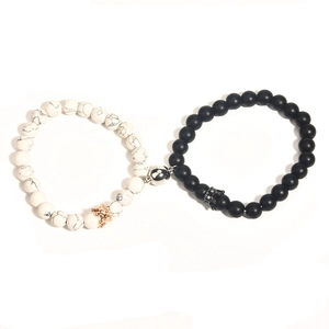 Detail of magnetic couple bracelets with white marble beads and black matte crown charms