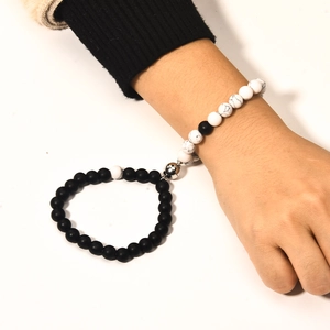 Close-up of matte black and white marble bead magnetic bracelets for couples on wrist