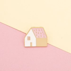 Detail van een emaille huisspeld met roze dak en witte muren op pastel achtergrond