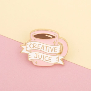 Detail van een roze emaille speld in de vorm van een koffiemok met Creative Juice