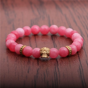 Close-up of pink agate beads bracelet featuring a golden skull and decorative spacers