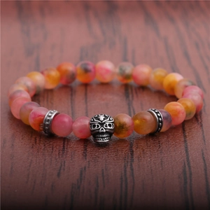 Agate skull bracelet featuring 8mm red and yellow gradient beads on a rustic wood surface
