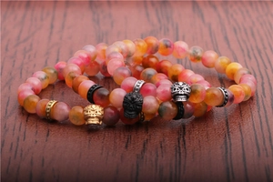 Macro shot of 8mm agate beads and metallic skull charms on a leather surface