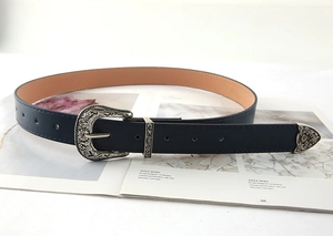 Close-up of vintage engraved silver buckle on dark blue leather belt with metal tip