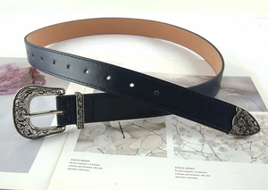 Detail view of navy blue leather belt with ornate silver Western floral buckle and metal tip