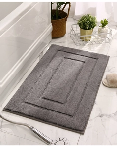 Graue Badezimmermatte mit Doppelrand auf Marmorboden neben der Badewanne