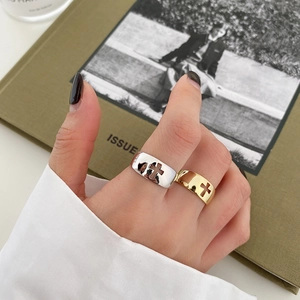 Detail of hollow cross wide rings in gold and silver finish worn on model hand