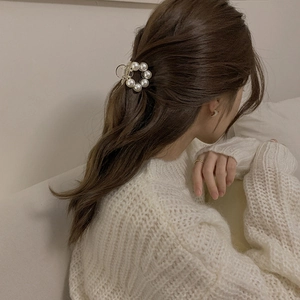 Elegant gold metal hair claw clip with white pearls shown on a woman's half-up hairstyle