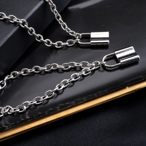 Macro shot of silver hip-hop chain necklaces with lock pendants on a black tray