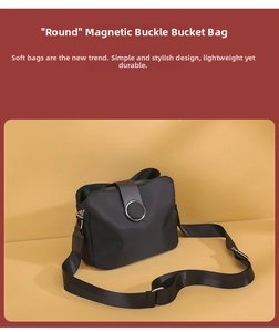 Close-up of black nylon bucket bag featuring a circular metallic magnetic closure and strap