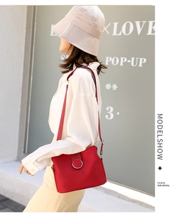 Detail of red nylon crossbody bag with silver buckle and adjustable strap on a model