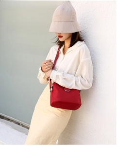 Outdoor lifestyle shot of a bright red mini nylon crossbody bag on a female model