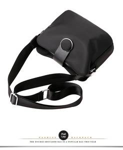 Detail of black nylon crossbody bag with silver round metal buckle on white background