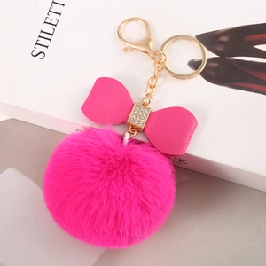 Close-up of fuchsia faux fur pompom keychain with a sparkling rhinestone bow detail