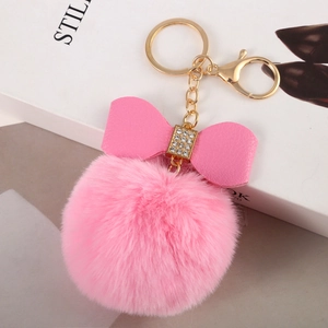Close-up of pink faux rabbit fur pom pom keychain with rhinestone leather bow detail