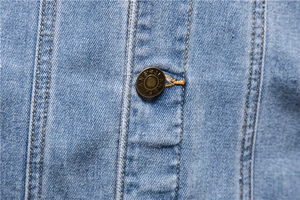 Macro shot of copper button with jeans lettering and yellow stitching on denim jacket