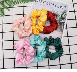 Flat lay of satin silk scrunchies in six vibrant colors on a trendy ins style background