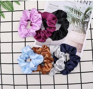 Detailed flat lay of colorful satin silk scrunchies on a minimalist white grid backdrop