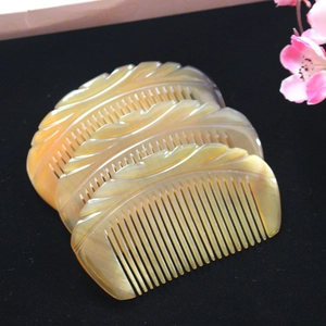 Macro shot of three half-moon horn combs with intricate carvings and natural texture