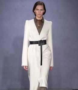 Detail view of stylish black knotted leather belt styled over a beige coat and shirt