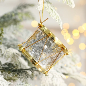 Golden Christmas drum ornament with silver glitter snowflakes on a snowy tree branch